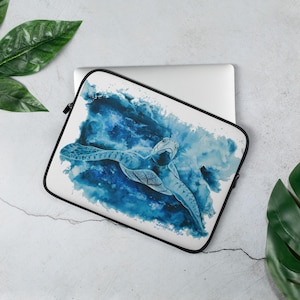 May include: A white laptop sleeve with a watercolour painting of a sea turtle in blue water. The sleeve has a black zip and trim. The words "Zomered Style" are printed in the bottom corner.
