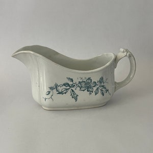 Puede incluir: Salsera de porcelana blanca con un diseño de vid floral en color turquesa. La salsera tiene un pico para verter y un asa decorativa. Un diseño clásico para servir salsas y salsas.