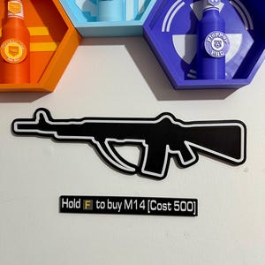 Puede incluir: Contorno en blanco y negro de un rifle con el texto "Hold F to buy M14 [Cost 500]" debajo. Encima, estantes hexagonales con botellas de colores.