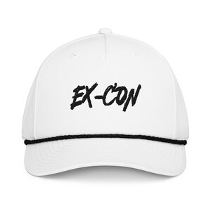 May include: White baseball cap with the text "EX-CON" in black, bold, handwritten-style lettering. The cap has a black rope detail along the brim and a curved visor. The hat is a classic, casual accessory.
