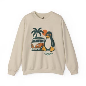 May include: A cream-coloured sweatshirt with a cartoon penguin wearing sunglasses, beside an orange and white van with a surfboard. A palm tree and sun are in the background. The van has the word "LINUX" on it.