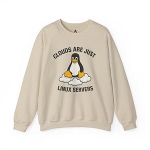 Pode incluir: Camisola bege com a frase "Clouds are just Linux Servers" e um desenho de um pinguim sobre nuvens. O pinguim é preto e branco com pés e bico amarelos. A camisola tem gola redonda e mangas compridas.