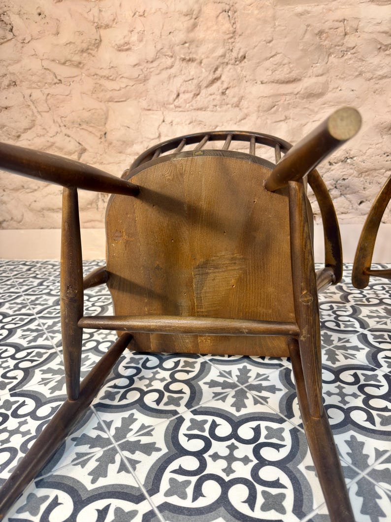 May include: A vintage wooden chair with a curved back and spindle detailing. The chair has a natural wood finish and a sturdy, traditional design. The legs are angled for stability, and the seat appears to be made of solid wood.