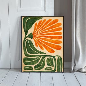 May include: Abstract floral art print featuring a large orange flower with green leaves and stem against a beige background. The artwork is framed in a black border, creating a striking contrast. The botanical illustration is a modern art piece.