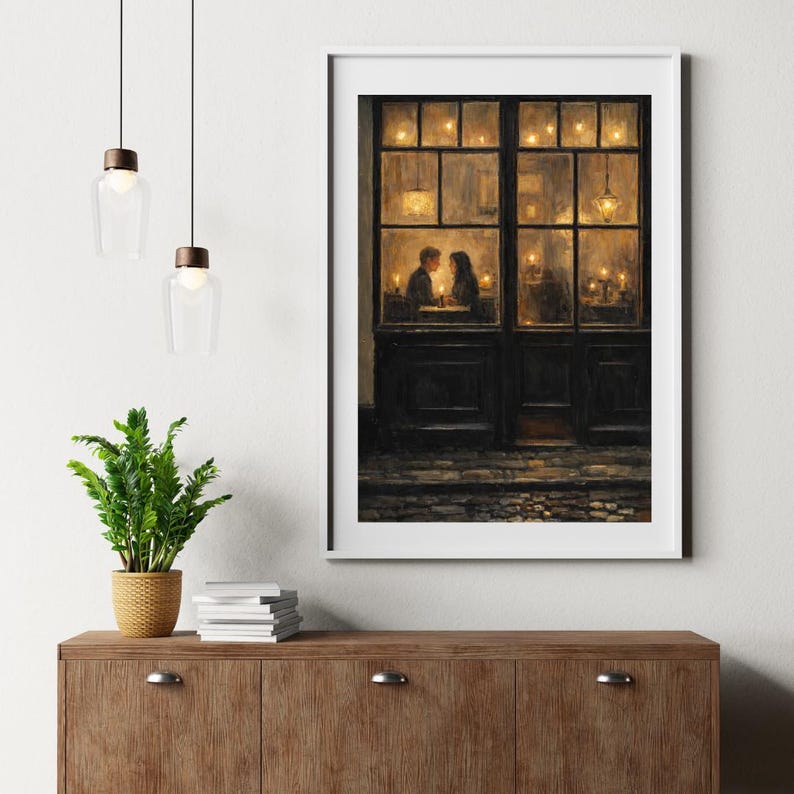 May include: A framed print depicts a romantic scene of a couple dining in a warmly lit restaurant. The artwork features a dark wooden door and windows, with soft candlelight illuminating the interior. The overall color palette is warm, with a focus on the couple.
