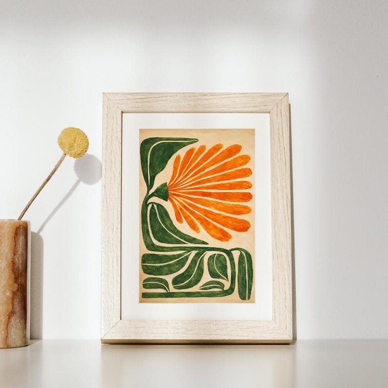May include: Abstract floral art print in a light wood frame. The artwork features a stylized orange flower with green leaves and stems against a beige background. The print is displayed on a white surface.
