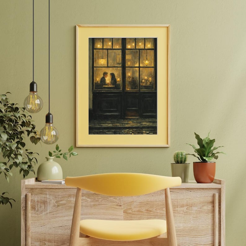 May include: A framed print of a romantic scene. The artwork depicts a couple dining in a warmly lit restaurant, viewed through a window. The frame is a light yellow color, and the overall aesthetic is cozy and inviting.