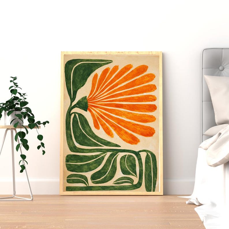 May include: A framed art print featuring a stylized orange flower with green leaves against a beige background. The artwork is in a wooden frame and is displayed in a room with a plant and a bed.