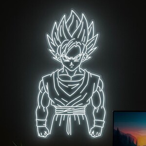 Peut inclure: Sculpture lumineuse au néon blanc représentant un personnage d'anime masculin aux cheveux hérissés et à l'expression déterminée. La silhouette se détache sur un fond sombre, mettant en valeur sa musculature et sa tenue.