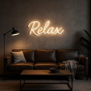 Peut inclure: Un salon avec un canapé en cuir marron, une table basse en bois et un lampadaire noir. Le mot "Relax" est affiché dans une lumière néon chaude et brillante sur le mur au-dessus du canapé. Une couverture et un oreiller gris ajoutent à l'atmosphère chaleureuse.