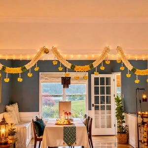 May include: A dining room decorated with floral garlands and string lights. The garlands are white and yellow, with green accents. The room has a table set for a meal, with a window in the background.
