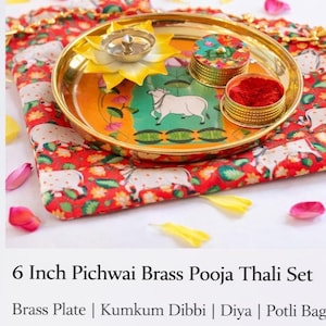 May include: A 6-inch brass pooja thali set featuring a round brass plate with a central cow illustration, a yellow lotus-shaped diya, and a small lidded container filled with red kumkum powder, all resting on a red fabric potli bag with cow motifs.