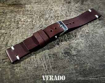 May include: A brown leather watch strap with white stitching and a silver buckle. The strap is made of a rich, dark brown leather and features a classic design. The word "VERADO" is printed at the bottom.