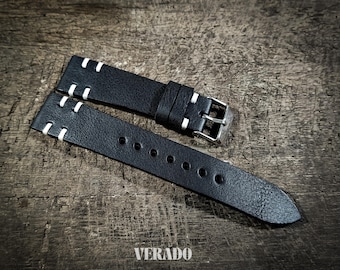 May include: Black leather watch strap with white stitching and a silver buckle. The strap has a textured surface and is shown on a wooden background. The brand name "VERADO" is visible.