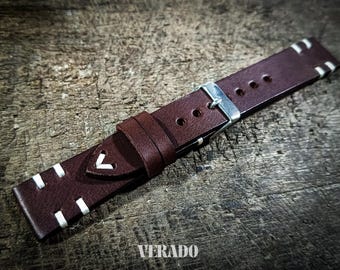 May include: A brown leather watch strap with white stitching and a silver buckle. The strap features a stitched V-shaped design and the word "VERADO" is printed on the strap.