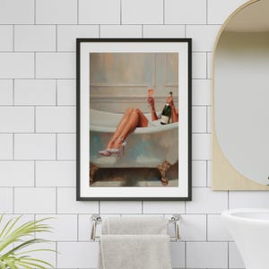 May include: Framed art print of a woman in a bathtub, holding a champagne bottle and a glass. She wears high heels with sparkling embellishments. The artwork has a vintage aesthetic, with a light color palette and ornate bathtub.