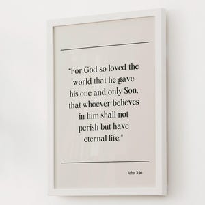 Peut inclure: Une affiche encadrée avec un cadre blanc présente une citation de Jean 3:16. Le texte noir est sur un fond beige clair. La citation commence par "Car Dieu a tant aimé le monde..." et se termine par "la vie éternelle."