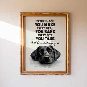 May include: Framed print with a gold-colored wooden frame. The print features a black Labrador Retriever illustration and the text: "EVERY SNACK YOU MAKE, EVERY MEAL YOU BAKE, EVERY BITE YOU TAKE, I'll be watching you."