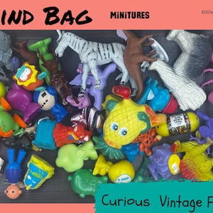 May include: A selection of colourful miniature toys, including a zebra, fish, and various creatures, are displayed in a dark container. The words "BLIND BAG" and "MINITURES" are at the top. The text "Curious Vintage Finds" is at the bottom.