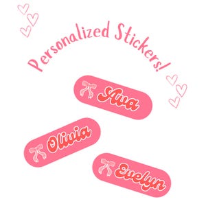 May include: Pink personalized stickers with names Ava, Olivia, and Evelyn in a retro font. Each sticker has a bow graphic. The words "Personalized Stickers!" are written in a curved font above the stickers. Pink hearts are scattered around the stickers.