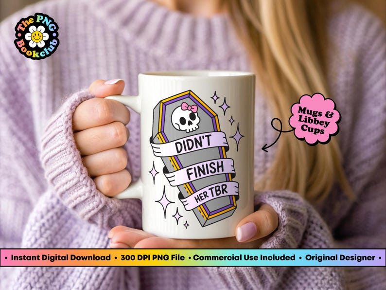May include: White ceramic mug featuring a coffin design with a skull, a pink bow, and the text "DIDN'T FINISH HER TBR." The mug has a handle and is decorated with stars. The mug is held by a person.