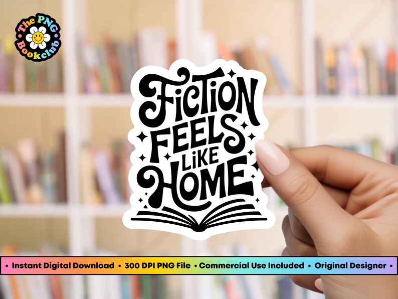May include: A white sticker with the text "Fiction Feels Like Home" in a bold, stylized font. The design includes stars and an open book at the bottom. The sticker is held against a blurred background of bookshelves.