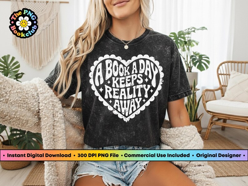 Pode incluir: Camiseta preta com um gr&aacute;fico branco em forma de cora&ccedil;&atilde;o que diz "A BOOK A DAY KEEPS REALITY AWAY". A camiseta tamb&eacute;m tem o texto "The PNG Bookclub" em um logotipo circular. A camiseta &eacute; usada por uma pessoa.