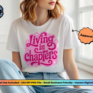 May include: A white short-sleeved t-shirt featuring a pink graphic design on the chest with the text Living in chapters. The design includes small star accents and a light pink outline. The shirt is paired with blue denim jeans.