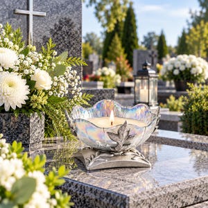 Könnte beinhalten: Ein dekorativer Kerzenhalter mit einer irisierenden, gewellten Glasschale und einem silberfarbenen Metallsockel mit Blatt- und Rankenmotiven. Die Schale enthält eine brennende Kerze mit sichtbarer Flamme und steht auf einer grauen Granitfläche.