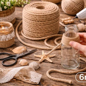 May include: A craft scene with natural elements. A clear glass bottle is wrapped with jute twine, alongside a roll of twine, scissors, seashells, and a starfish. A candle in a jar and a basket with plants are also present. The twine is 6mm thick.