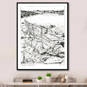 Op de afbeelding: Zwart-wit pen- en inkttekening van een kustlandschap. Een houten reling strekt zich uit in het water over een rotsachtige kustlijn. Het kunstwerk is zwart omlijst en wordt tentoongesteld op een wit oppervlak.