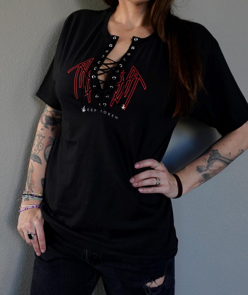 Puede incluir: Camiseta negra con un gr&aacute;fico rojo y un escote con cordones. El gr&aacute;fico presenta el texto "KEEP TOKEN".