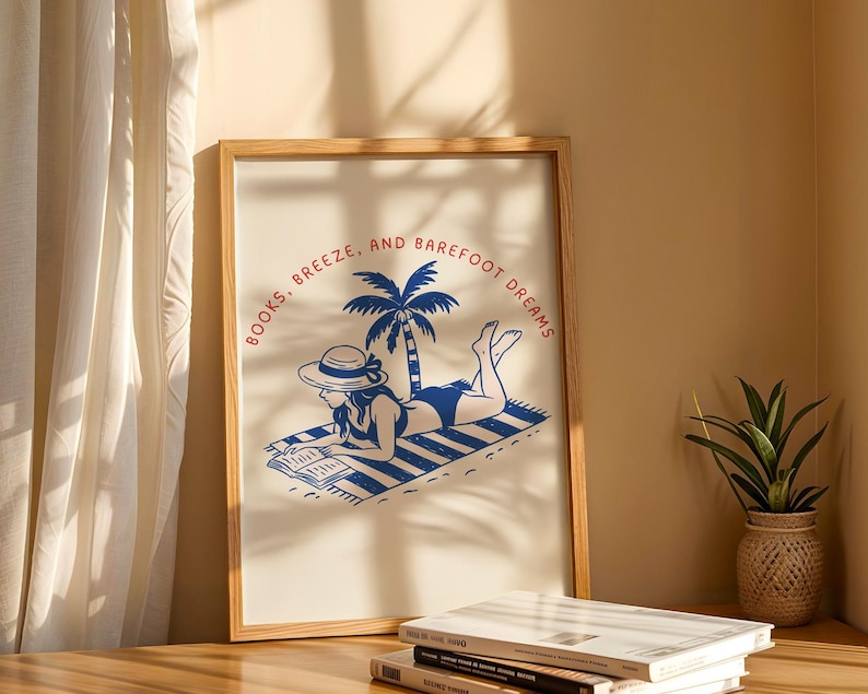 May include: A framed art print with a blue and white illustration of a person reading on a beach towel under a palm tree. The text "BOOKS, BREEZE, AND BAREFOOT DREAMS" is printed in a circular pattern around the image.