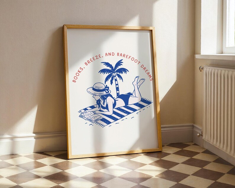 May include: Wooden framed art print with a blue and white illustration of a person reading on a beach towel. The text reads "Books, Breeze, and Barefoot Dreams" in a circular design around a palm tree.