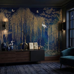 May include: A dark blue wallpaper mural featuring golden weeping willow trees, white cranes, and butterflies. The scene includes a dark wood sideboard with blue ceramic vases, two gold crane figurines, an open book, and a small candle in a glass holder.