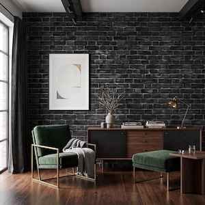 May include: A dark green velvet armchair with a gold metal frame and a matching ottoman, positioned near a wooden sideboard, a small side table, and a framed abstract print on a black brick wall, featuring a gray throw blanket draped over the chair.