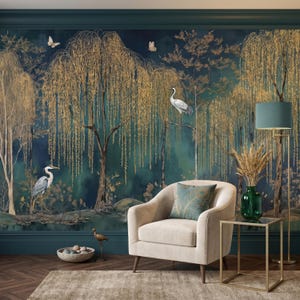 May include: A beige upholstered armchair with a teal peacock feather patterned cushion, positioned in front of a dark teal wallpaper mural depicting golden willow trees, white herons, and butterflies, with a green glass vase on a metal side table.