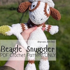 Puede incluir: Un juguete de crochet de perro beagle blanco y marrón con boina. El juguete tiene orejas, parches y detalles marrones. El texto "Beagle Snuggler PDF Crochet Pattern ONLY" se muestra en la imagen.