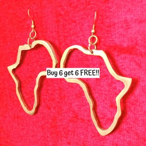 May include: Gold-colored earrings in the shape of the African continent, hanging from gold-colored hooks. The earrings are set against a red background. Text in the image reads: Buy 6 get 6 FREE!!