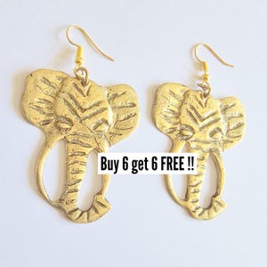 May include: A pair of gold-colored elephant-shaped earrings. The earrings have a textured surface and are suspended from gold-colored ear wires. The image includes the text "Buy 6 get 6 FREE !!".
