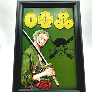 May include: Framed artwork featuring a green-haired character from the anime series One Piece, holding a sword. The artwork includes gold-colored embellishments and a green background. The frame is black.