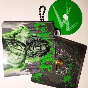 Puede incluir: Un conjunto de estuches de CD negros y grises y un CD verde. Los estuches presentan un gráfico de una persona con acentos verdes y la palabra "LOVE". El CD verde tiene un gráfico blanco.