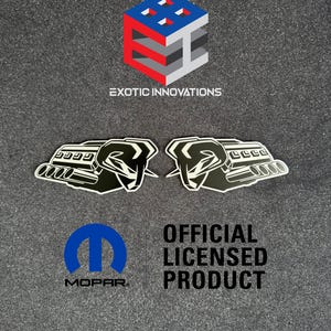 Puede incluir: La imagen presenta dos pegatinas de motor en blanco y negro con un diseño de cabeza de carnero. También se ven el logotipo de Mopar, el texto "OFFICIAL LICENSED PRODUCT" y el logotipo de "EXOTIC INNOVATIONS".