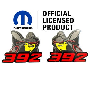 May include: Two Mopar 392 emblems featuring a stylised bee character with a yellow chest, black body, and red accents. Below the bee, the number 392 is displayed in bold red font. The Mopar logo and the text OFFICIAL LICENSED PRODUCT are visible.