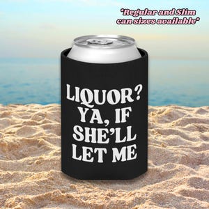 Op de afbeelding: Een zwarte schuimrubberen blikkoeler met de witte tekst LIQUOR? YA, IF SHE'LL LET ME op de voorzijde. De bovenkant van een zilverkleurig aluminium blikje is zichtbaar. De tekst rechtsboven luidt Regular and Slim can sizes available.