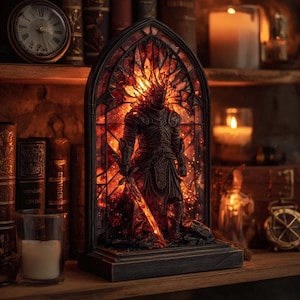 May include: A decorative stained glass lamp featuring a warrior figure in armor, holding a sword. The lamp has a dark wooden base and a fiery red and orange glow emanating from within. The lamp is set on a wooden shelf with books and candles.
