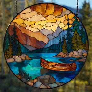Pode incluir: Painel redondo de vitral retratando uma serena cena lacustre. A obra apresenta uma canoa de madeira sobre água turquesa, cercada por montanhas e árvores perenes. O céu transita do amarelo para o laranja. Moldura de metal preta e corrente suspensa.