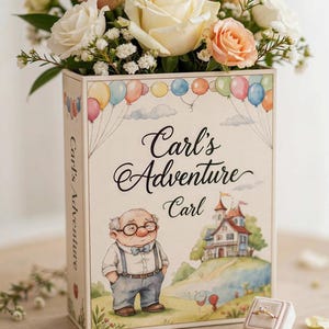 Può includere: Una scatola rettangolare con un'illustrazione ad acquerello di un uomo anziano con occhiali, una casa e palloncini colorati, con il testo Carl's Adventure Carl. Un bouquet di rose bianche e color pesca è inserito all'interno e un anello è in un cofanetto.