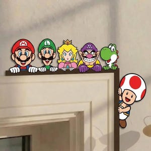 May include: A set of decorative wall decals featuring Mario, Luigi, Princess Peach, Wario, and Yoshi lined up along the top edge of a door frame, with Toad positioned on the side edge, all depicted in their classic colourful character designs.