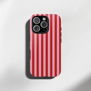 May include: A pink and red striped phone case. The case has a glossy finish and features a camera cutout with three lenses and a flash. The design consists of vertical stripes in alternating shades of pink and red.
